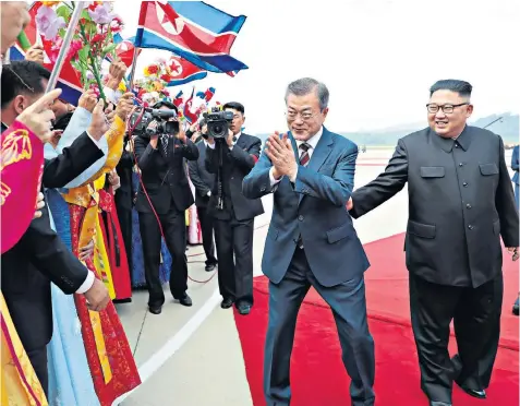  ??  ?? The South Korean President, Moon Jae-in, centre, is greeted yesterday at Sunan Airport in Pyongyang by North Korea’s leader Kim Jong-un, right