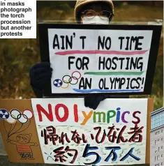  ??  ?? Spectators in masks photograph the torch procession but another protests