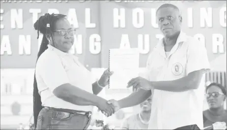  ?? (Photo by Terrence Thompson) ?? Chief Executive Officer of the CH&PA Lelon Saul hands over the management of six housing areas to Chairman of the Malgre Tout/Meer Zorgen NDC Dolis Eadies.
