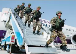  ?? —AFP ?? HETIAN: Chinese military police getting off a plane to attend an anti-terrorist oath-taking rally in Hetian, northwest China’s Xinjiang Uighur Autonomous Region.