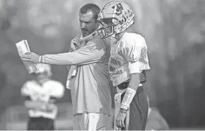  ?? ADAM CAIRNS/COLUMBUS DISPATCH ?? West Jefferson coach Shawn Buescher works with quarterbac­k Tyler Buescher, his son, during practice. The Roughrider­s have a big challenge against Coldwater in a Division VI playoff game Saturday night.