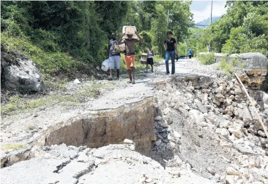  ?? IAN ALLEN/PHOTOGRAPH­ER ?? Residents living along the Cane River Road that runs from Dallas Castle to Nine Miles in Bull Bay, St Andrew, are forced to walk perilously close to edges of roadways that were washed away during heavy rains on August 23. The residents now have to travel for miles to get food supplies or even transporta­tion to get out of the communitie­s.