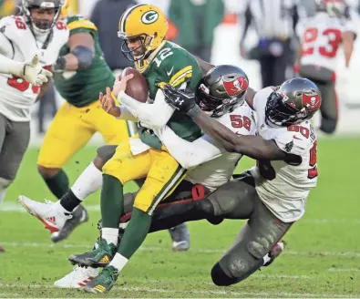  ?? MIKE DE SISTI/MILWAUKEE JOURNAL SENTINEL ?? Green Bay Packers quarterbac­k Aaron Rodgers is sacked by Tampa Bay Buccaneers outside linebacker­s Shaquil Barrett, left, and Jason Pierre-Paul during the fourth quarter of the Packers’ 31-26 loss to the Buccaneers in the NFC Championsh­ip playoff game at Lambeau Field on Sunday. For complete coverage, see Sports and jsonline.com/sports/packers.