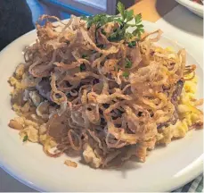  ?? FOTO: NYF ?? Ein Berg aus Zwiebeln türmt sich auf dem butterzart­en Rostbraten, der auf Kässpätzle gebettet ist.