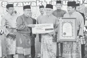  ??  ?? TAHNIAH: Tun Taib (dua kanan) menyampaik­an Anugerah Tokoh Maal Hijrah kepada wakil penerima sambil disaksikan Abang Johari (kiri) dan yang lain.