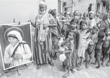  ?? BIKAS DAS/AP ?? Homeless people gather Thursday beside a portrait of St. Teresa, the founder of the Missionari­es of Charity, to collect food outside the order’s headquarte­rs in Kolkata, India. Thursday marked the birth anniversar­y of Mother Teresa, a Catholic nun who spent 45 years serving the poor, the sick, the orphaned and the dying. She was born in 1910 and died in 1997.