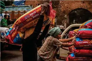  ?? (AFP/Getty) ?? Labourers push a cart loaded with sealed sacks of spice sin Ko l kata