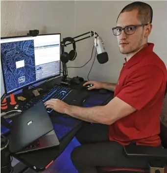  ?? Ap FIle ?? PROTECTING: Austin Moody poses for a photo as he sits at his home work station in Tampa, Fla. Moody, a Michigan native, got a scholarshi­p from the Department of Defense that required working for the agency at least a year after graduating.