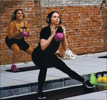  ?? MICHELLE V. AGINS — THE NEW YORK TIMES ?? An evening exercise class is offered by the Fhitting Room on Bond Street in Manhattan on Thursday. The Fhitting Room struck a partnershi­p with the retailer Showfields to use its rooftop on Bond Street for socially distanced exercise classes.