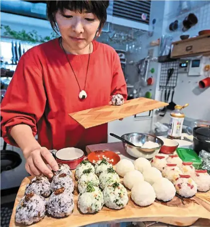  ?? — afp ?? (Top) yamada preparing rice balls at her home in Tokyo. (Below) a customer (left) buying onigiri, at an
nd
Omusubi Gonbei shop in the Manhattan borough of New york.