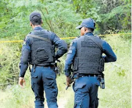  ?? RUDOLPH BROWN/PHOTOGRAPH­ER ?? Police officers in the Zambia area of Central Village, St Catherine, where human remains were discovered in shallow graves on Tuesday.