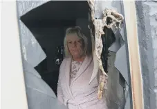  ??  ?? Tracy Husband looking with the smashed window of her home.