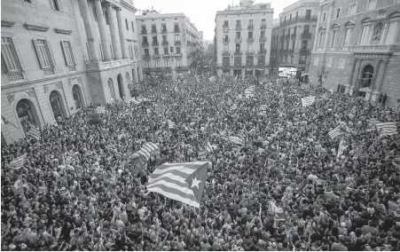  ??  ?? People wave pro-independen­ce flags outside the Palau Generalita­t in Barcelona, Spain, after Catalonia’s regional parliament voted to declare independen­ce for the Catalan Republic on Friday. The move was rejected by the Spanish government.