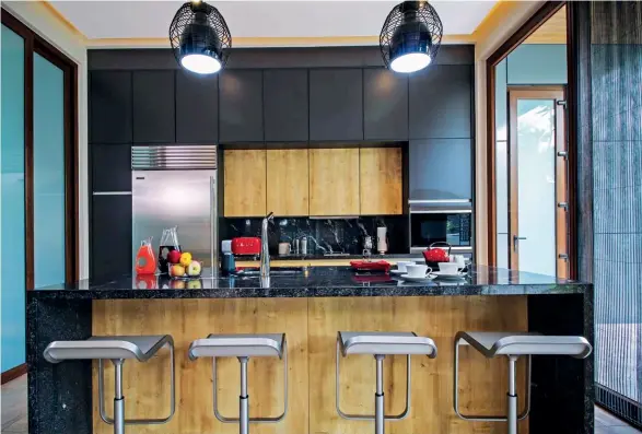  ??  ?? FROM LEFT The kitchen makes use of Foscarini Diesel Cage Lamps to illuminate the black leopard stone countertop, matched by Lem Piston stools in stainless steel. A vibrant red vintage-style toaster by Smeg strikes a contrast with the Siematic S2K...