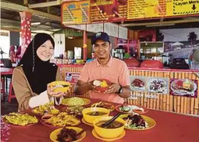  ?? PIC BY MOHD SYAFIQ RIDZUAN AMBAK ?? Mohd Rizal Ghazali and Saadiah Abdul Aziz showing the dishes offered at ‘Master Cendol Restoran Tambah Percuma’ in Taman Rusila, Marang, last week.