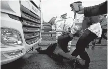  ?? JOHN SIBLEY • REUTERS ?? Police officers drag a person lying down in front of a lorry Wednesday at the Port of Dover in Britain as European Union countries impose a travel ban from the United Kingdom amid the coronaviru­s disease outbreak.