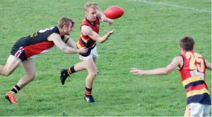  ??  ?? Longwarry’s Kane Oldham fires out a handpass to teammate Riley Rundell during the Crows’ four-point win over Nyora.