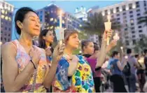  ?? RICARDO RAMIREZ BUXEDA/ORLANDO SENTINEL ?? Sam Jitaree, left, and Devi Thompson of Orlando hold candles at a vigil in Orlando one day after the mass shooting at Pulse nightclub.