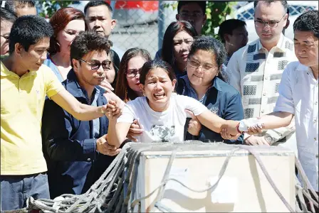  ?? (AFP) ?? Jessica (center), sister of Filipina worker Joanna Demafelis whose body was found inside a freezer in Kuwait, cries in front of the wooden casket containing her body shortly after arriving at the internatio­nal airport in Manila on Feb 16, while another...
