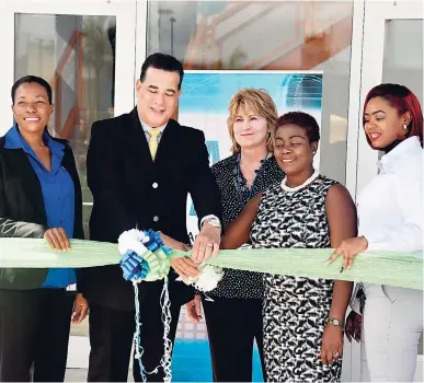  ?? MARK TITUS PHOTO ?? Mayor of Montego Bay Homer Davis shares ribbon cutting duties with Gloria Henry (second right) president of the Business Process Industry Associatio­n of Jamaica at the opening ceremony of Advanced Call Centre Technologi­es newest facility at Barnett Tech Park in Montego Bay yesterday. Sharing in the moment are directors of operations Marie Whyte (left), Yanique McKenzie (right) and Susan Parker, the company’s executive vice president.