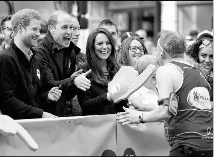  ?? AP file Photo ?? Prince William, his wife, Kate, and brother, Prince Harry, (left) encourage runners at a Heads Together cheering point along the route of the 2017 London Marathon in London. Heads Together is a mental-health charity supported by the three British royals.