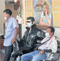  ??  ?? Taxi drivers rest near a masked Elvis Presley mannequin near Pak Khlong Talat flower market yesterday.