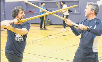  ?? MITCH MACDONALD/THE GUARDIAN ?? Evan Hill, left, and Michael Smallwood, right, battle with some wooden long swords during a Maritime Sword School practice at St. Jean Elementary School in Charlottet­own on Sunday night.