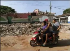  ?? LUIS ALBERTO CRUZ - THE ASSOCIATED PRESS ?? Residents drive by a collapsed building felled by a massive earthquake, in Juchitan, Oaxaca state, Mexico, Friday. One of the most powerful earthquake­s ever to strike Mexico has hit off its southern Pacific coast, killing at least 32 people, toppling...