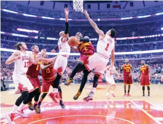  ??  ?? SPLITTING THE DEFENSE: Cleveland Cavaliers guard Kyrie Irving, center, drives between Chicago Bulls forward Taj Gibson, left, and guard Derrick Rose, right, during the first half at the United Center on Friday. (USA TODAY Sports)