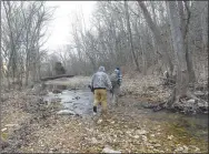  ?? Flip Putthoff/NWA Democrat-Gazette ?? Chris Denham (left) and Gary Wellesley follow Spec across a creek Feb. 17 on the hunt for squirrels.