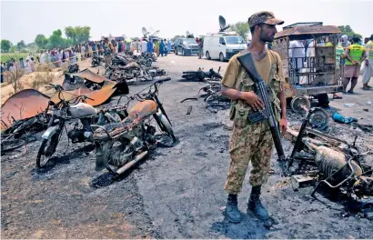  ?? AFP ?? A soldier stands guard amid burnt out cars and motorcycle­s at the scene of an oil tanker explosion in Bahawalpur on Sunday. —
