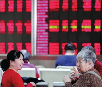  ?? WANG JING / CHINA DAILY ?? Investors talk about stock prices at a securities brokerage firm in Beijing on Monday.