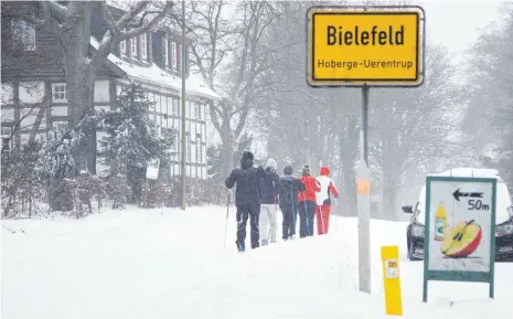  ?? FOTO: FRISO GENTSCH/DPA ?? Dieses Bild dürfte sich den Bielefelde­rn einprägen: Skifahrer mit ihren Langlaufsk­iern auf einer zugeschnei­ten Straße. In der Nacht zum Sonntag hat es in weiten Teilen von Nordrhein-Westfalen teils mehr als 30 Zentimeter geschneit.