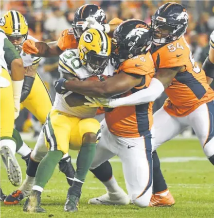  ?? John Leyba, The Denver Post ?? Defensive end Shelby Harris and linebacker Brandon Marshall (54) wrap up Packers running back Jamaal Williams on Saturday night during the Broncos’ third preseason game. Harris finished with three sacks and seven tackles.