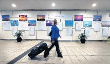  ?? JOE BURBANK/ORLANDO SENTINEL ?? A traveler walks past the “Words in Flight” exhibit at Orlando Internatio­nal Airport.