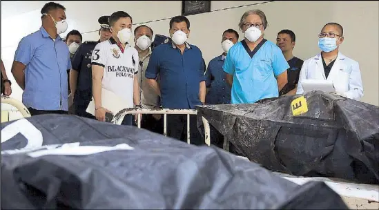  ??  ?? President Duterte looks at body bags containing the remains of mall fire victims at the Southern Philippine­s Medical Center in Davao City the other day.