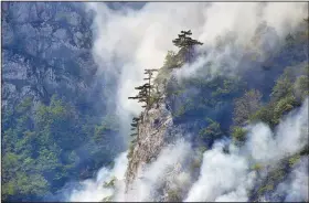  ?? (AP/Risto Bozovic) ?? Smoke rises Monday from a wildfire burning in the mountains near the Piva lake, in northwest Montenegro. Climate scientists say there is little doubt that climate change is driving extreme events such as heat waves, droughts, floods and storms.