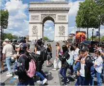  ?? Michel Euler/Associated Press ?? Tourists cross the Champs-Elysees avenue with the Arc de Triomphe in background in Paris.
