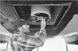  ?? BRITTANY PETERSON/AP ?? Airborne Snow Observator­ies engineer Dan Berisford cleans a laser snow-mapping device mounted under an airplane last month in Gunnison, Colorado.