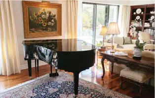  ??  ?? A large still-life oil painting depicting flowers in Belgium hangs behind a baby grand piano in the condo.