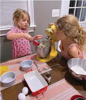  ?? Photo courtesy Danielle McWilliams via AP ?? Danielle McWilliams’ daughters Reese, 7, right, and Remi, 4, cook at their New Jersey home. Along with the usual cupcakes, crispy treats and from-scratch cookies, they make tarallis, an Italian family traditiona­l treat that’s a cross between a breadstick, bagel and pretzel.