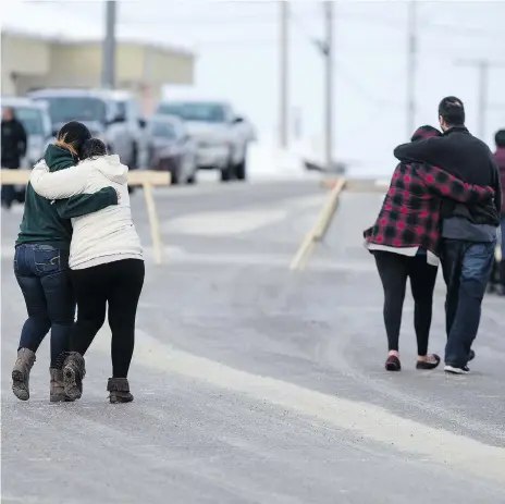  ?? LIAM RICHARDS ?? Community members walk past RCMP barricades outside the La Loche courthouse Friday, where a judge announced she would sentence a young man as an adult in the 2016 school shootings. Security was tight, with those allowed into the courtroom passing...