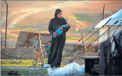  ??  ?? A Syrian refugee cradles her child at the Ain Issa camp