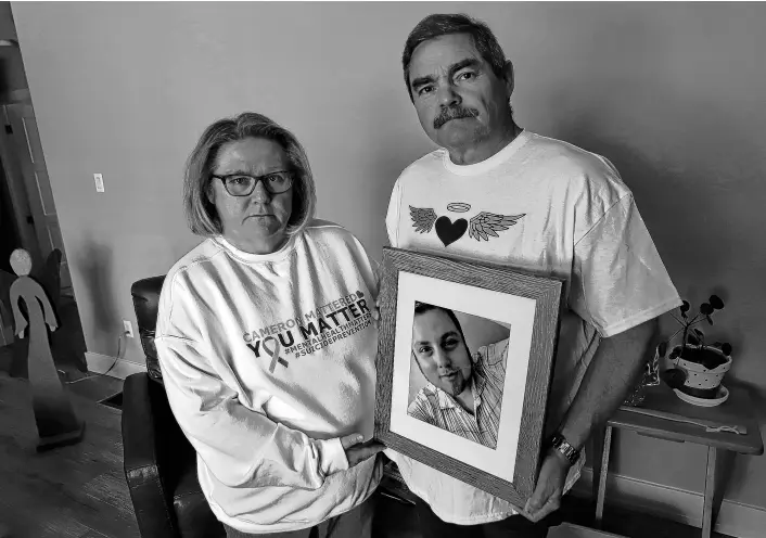  ?? TIM KROCHAK ■ THE CHRONICLE HERALD ?? Michele and Brian Haire hold a photo of their late son, Cameron, in their Lower Sackville home. Cameron took his life last year at the age of 26.