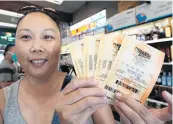  ?? RICH PEDRONCELL­I AP ?? Jennifer Ho displays the 50-plus tickets she bought Friday at liquor store in Sacramento, Calif.