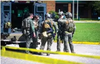  ?? The Associated Press ?? ■ Members of the Virginia State Police SWAT Team gather behind a Bearcat tactical vehicle after clearing Heritage High School in Newport News, Va., Monday following a shooting at the school.