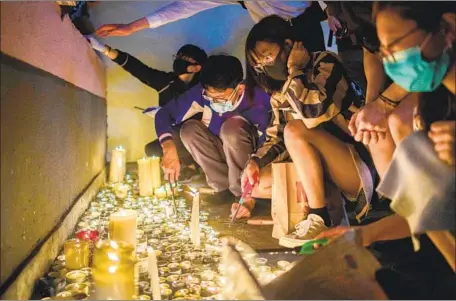  ?? Photograph­s by Anthony Wallace AFP/Getty Images ?? THOUSANDS of mourners waited to light candles at the parking garage where Alex Chow Tsz-lok, 22, fell three stories to his death.