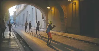  ??  ?? Children wearing masks play baseball in Old Havana, Cuba.