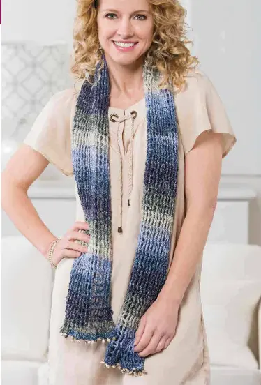  ??  ?? The openwork ribbed pattern of this summer scarf, worked in shimmering variegated blue yarn, mimics the movement of ocean waves. A “fringe” of shell beads completes the beachy theme.