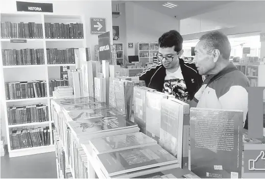  ??  ?? ● Un padre con su hijo, exploran los libros de Historia.